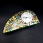 Underside of vintage pāua shell clock showing wear to felt base