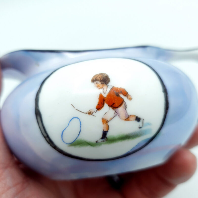 Antique British lustreware cream jug with iridescent blue and pink glaze and child playing with hoop decoration